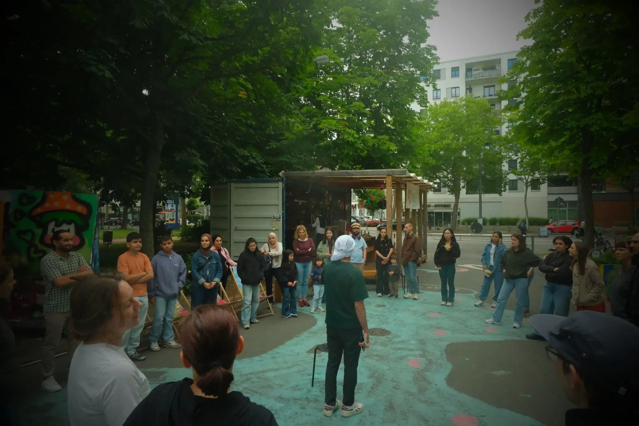 Teilnehmende stehen draußen im Kreis und hören einer Dabke-Workshopleitung zu