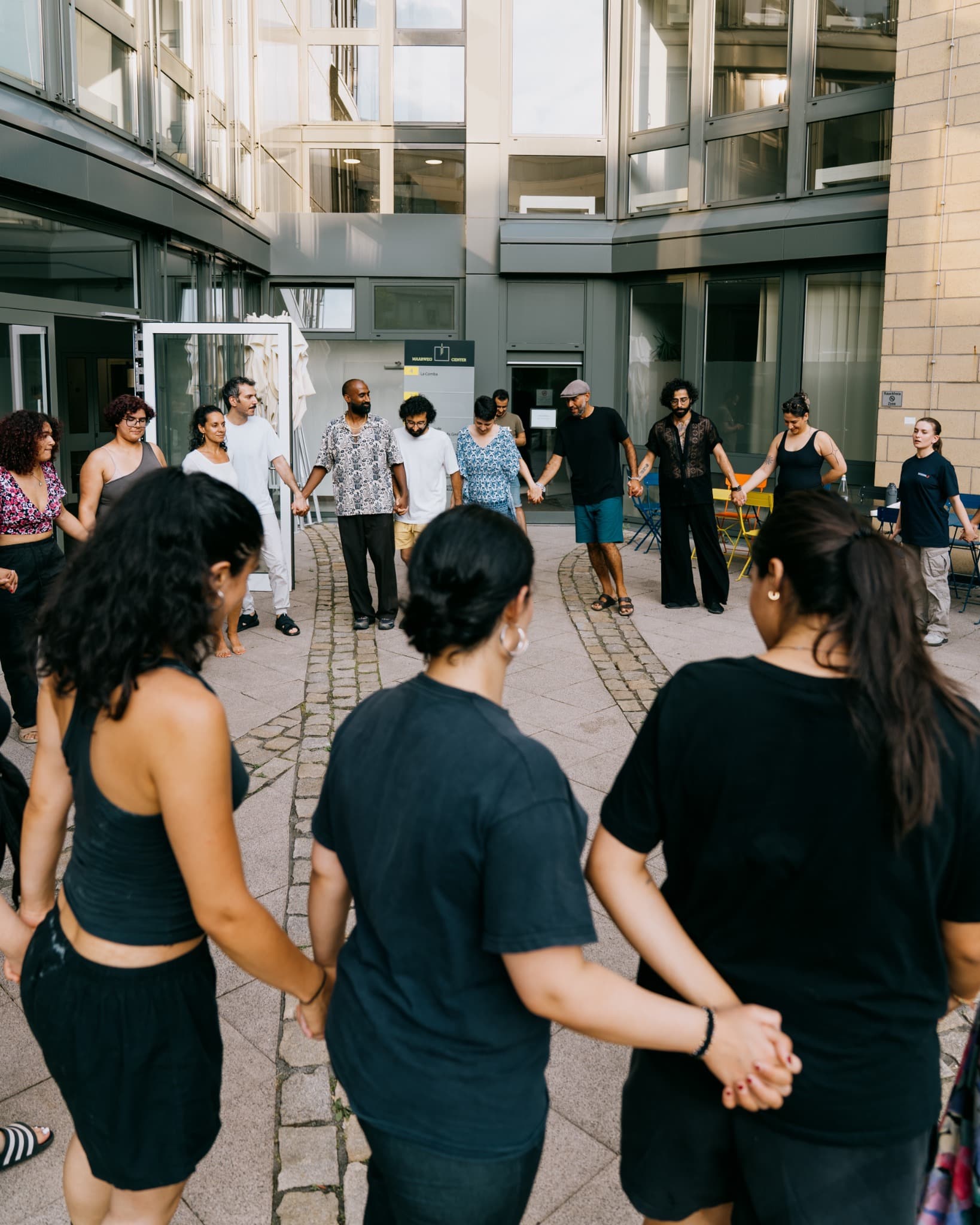 A diverse group holding hands in a circle during a Dabke workshop