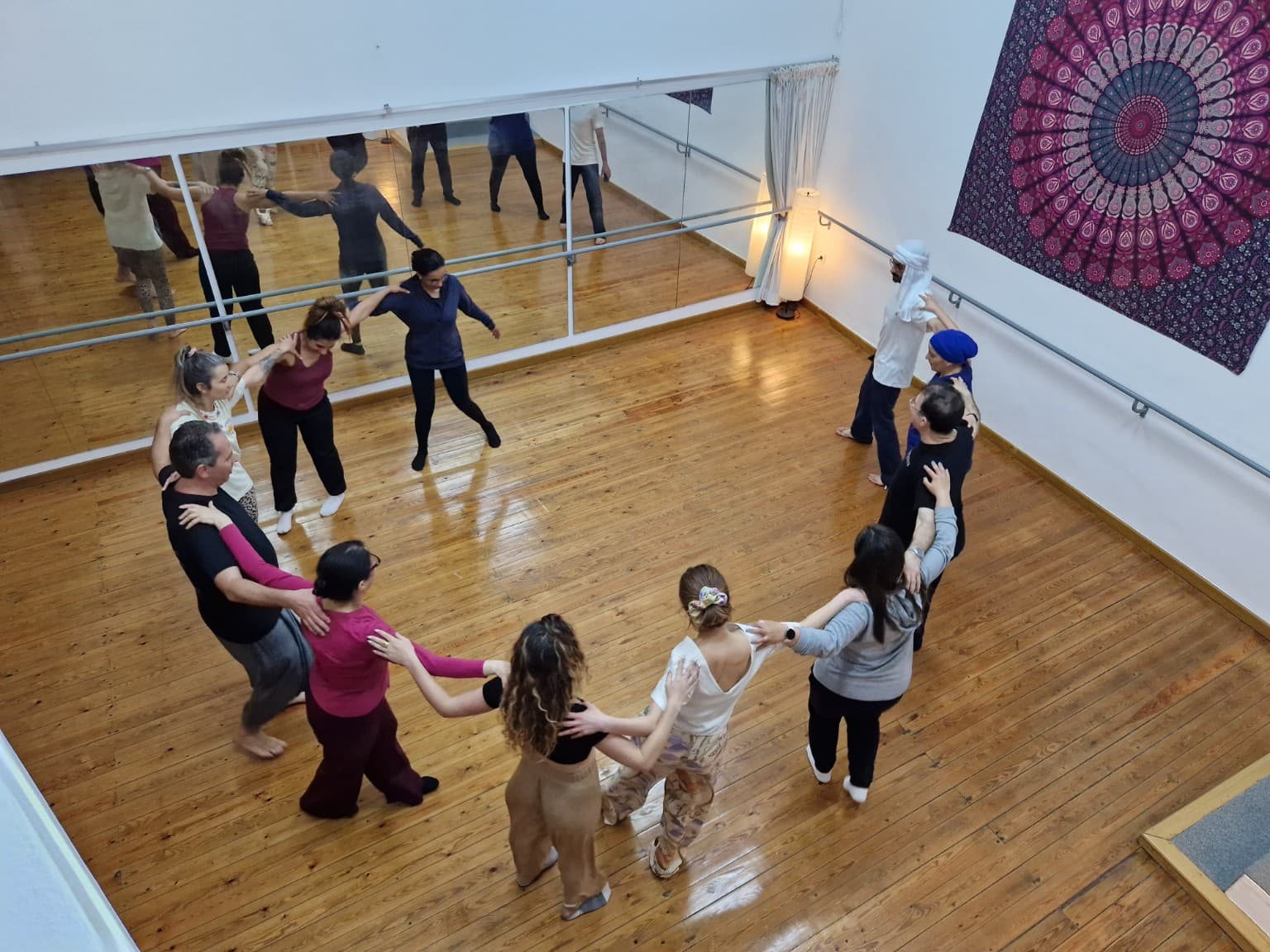 Dabke workshop participants dancing together in a circle in a wooden-floor studio